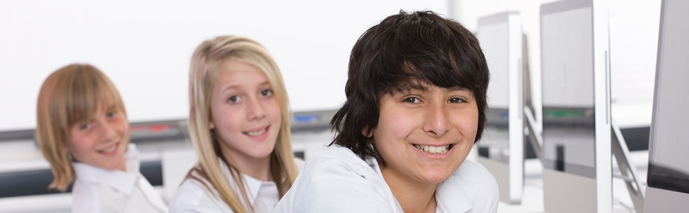 3 teenage students who have been working on computers looking at the camera.