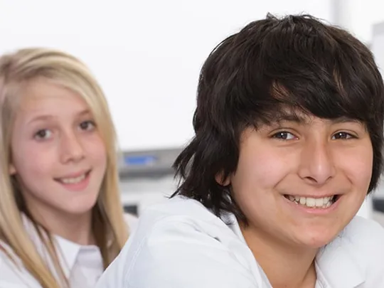 3 teenage students who have been working on computers looking at the camera.