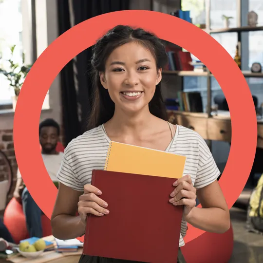 Smiling female IB student holding notebooks, representing Pamoja's dedication to supporting every IB student in their academic journey.