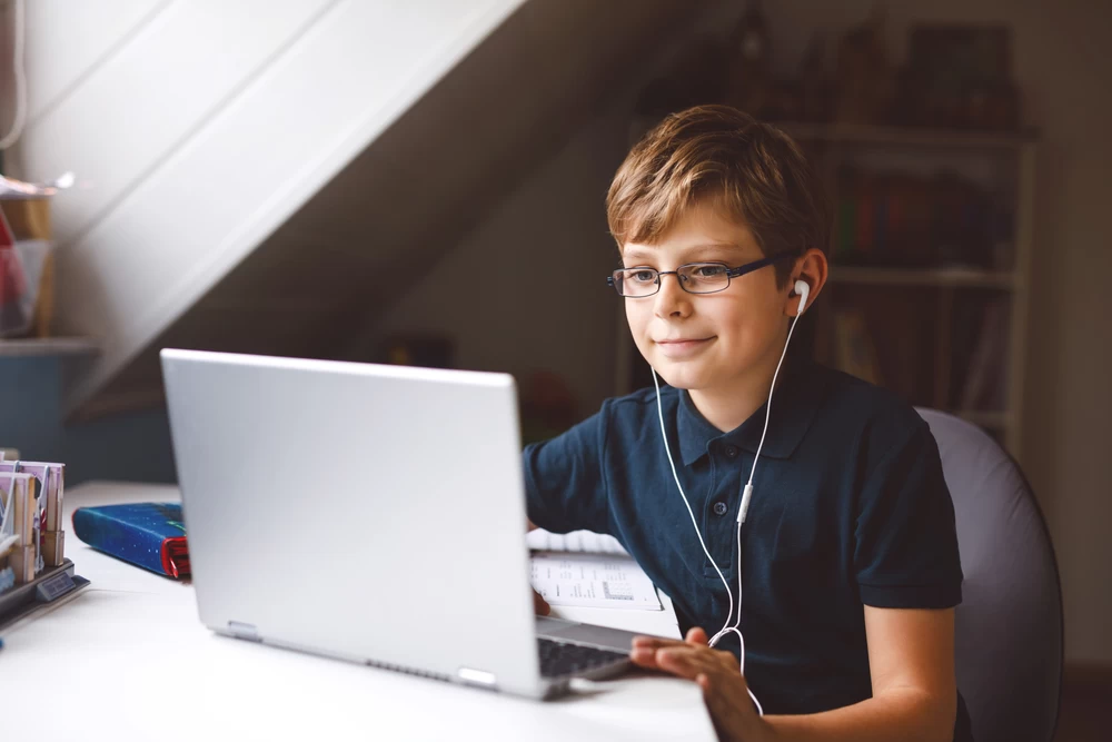 Young boy on laptop, with earphones in.