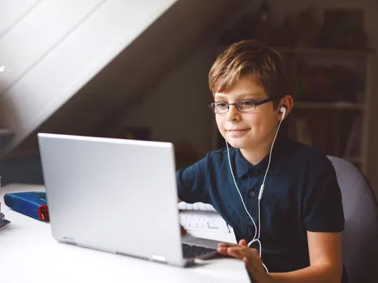 Young boy on laptop, with earphones in.