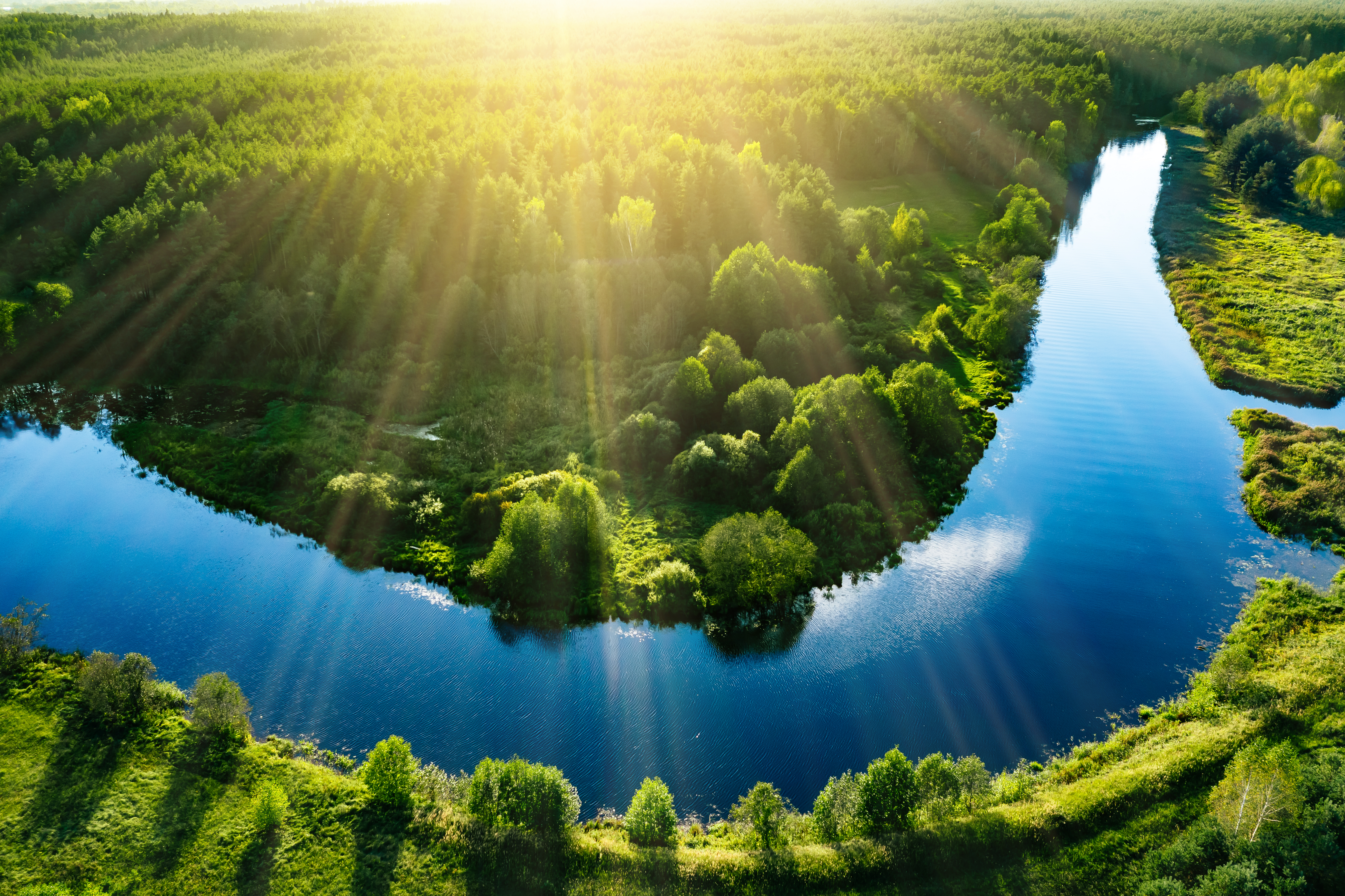 Photo of a winding river surrounded by green fields.