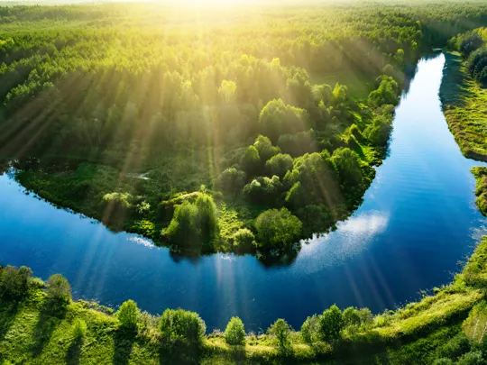 Photo of a winding river surrounded by green fields.