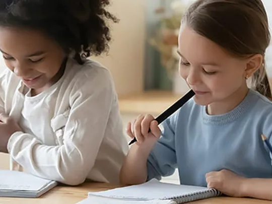 Two young girls writing together.