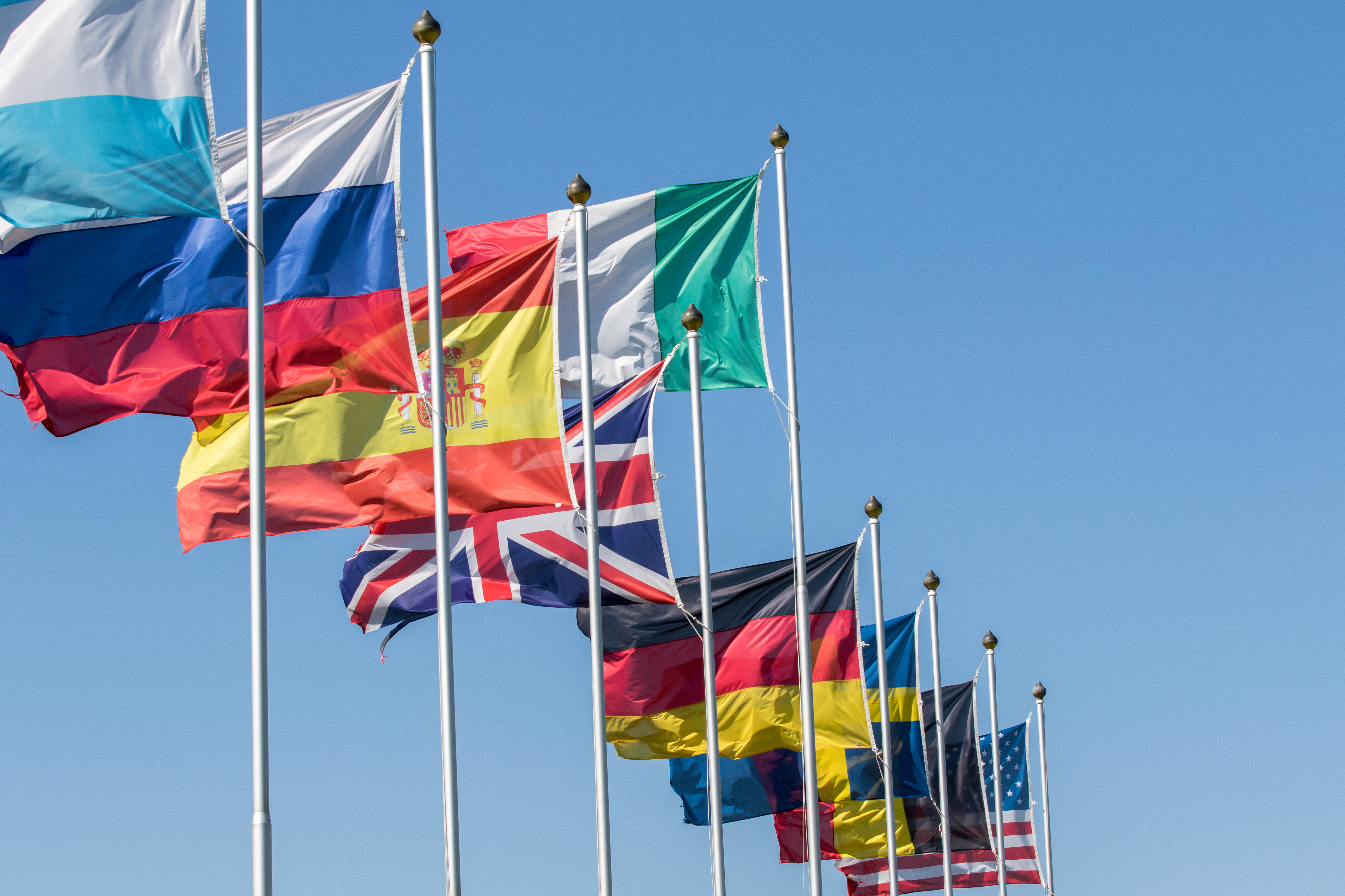 A photo of international flags flying on masts.