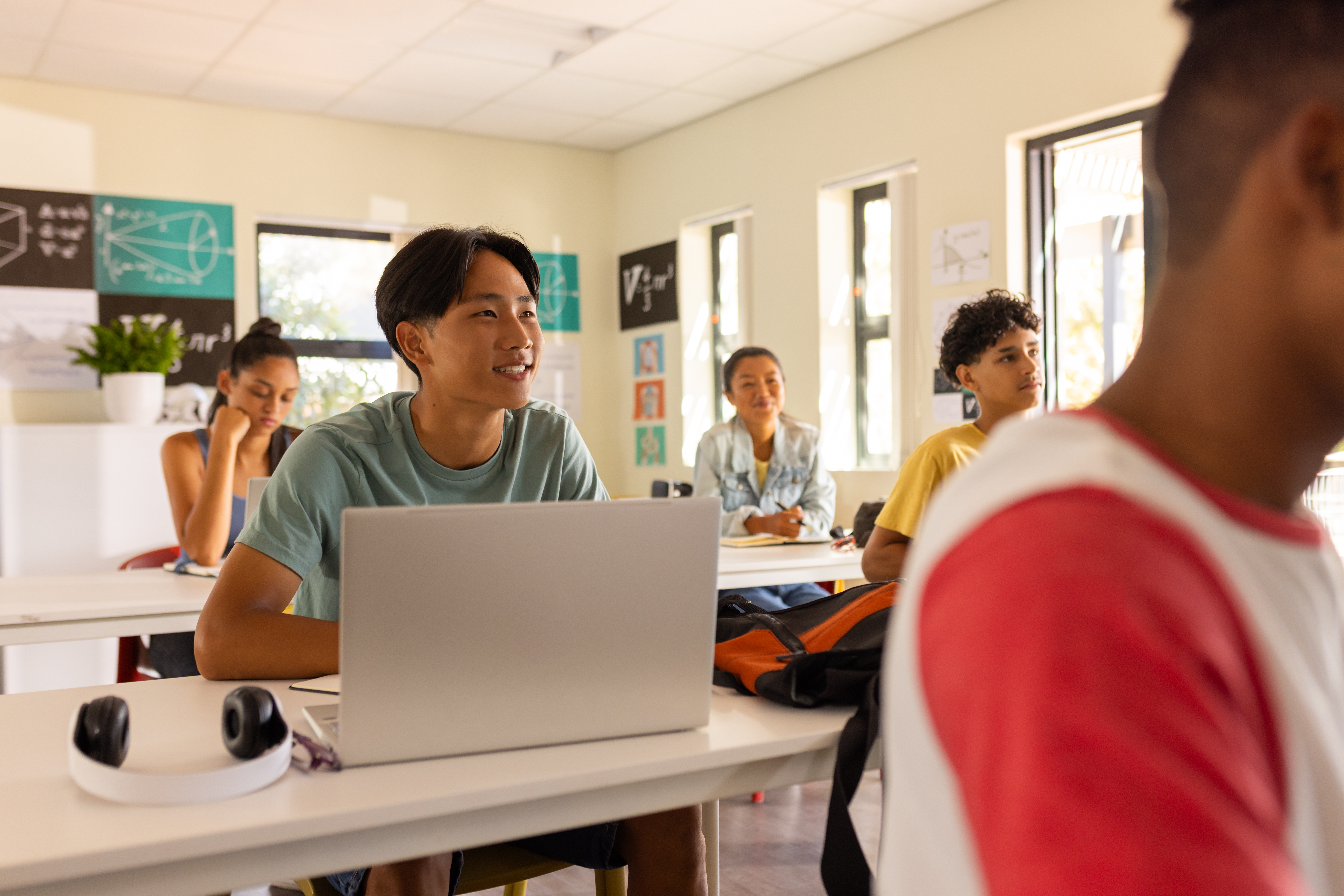 Students working on laptops in a bright, modern classroom of a pamoja school