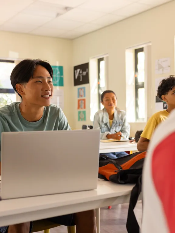 Students working on laptops in a bright, modern classroom of a pamoja school