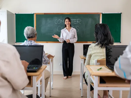 a young female teacher standing in front of a chalkboard that reads