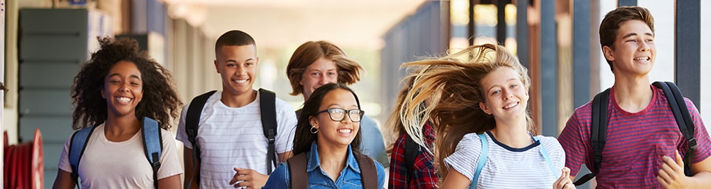 A group of teenagers walking through a hallway.