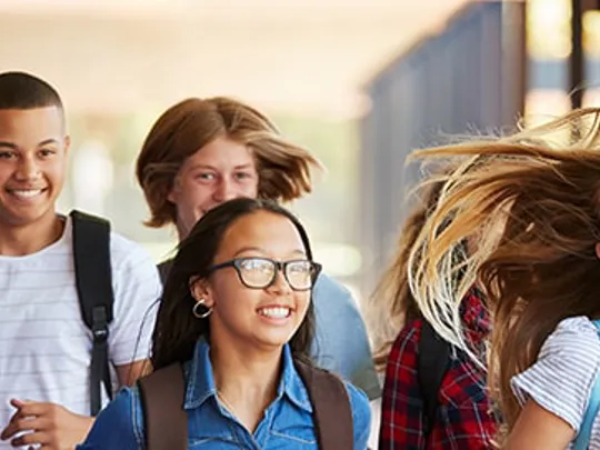A group of teenagers walking through a hallway.