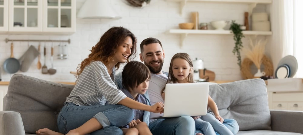 An entire family sat around a laptop. 