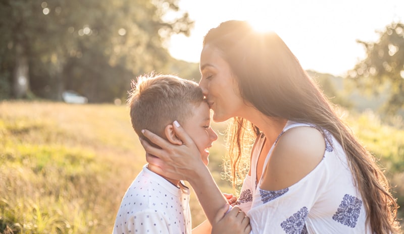 A mother kissing her son on the forehead. 
