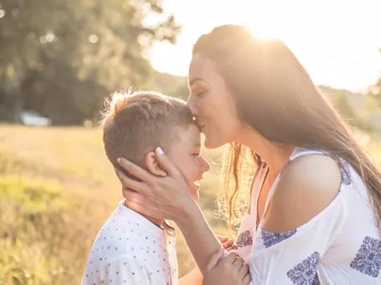 A mother kissing her son on the forehead.
