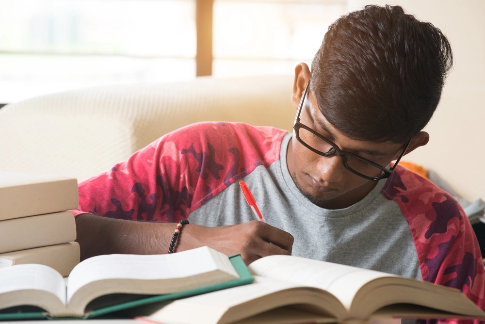 Young male student studying and making notes.