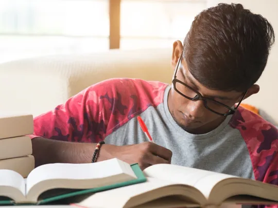 Young male student studying and making notes.
