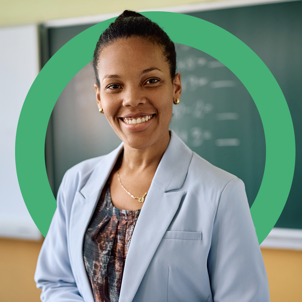 Smiling female educator in front of a classroom chalkboard, representing a trusted partner for schools