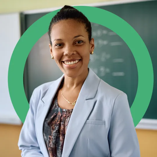 Smiling female educator in front of a classroom chalkboard, representing a trusted partner for schools