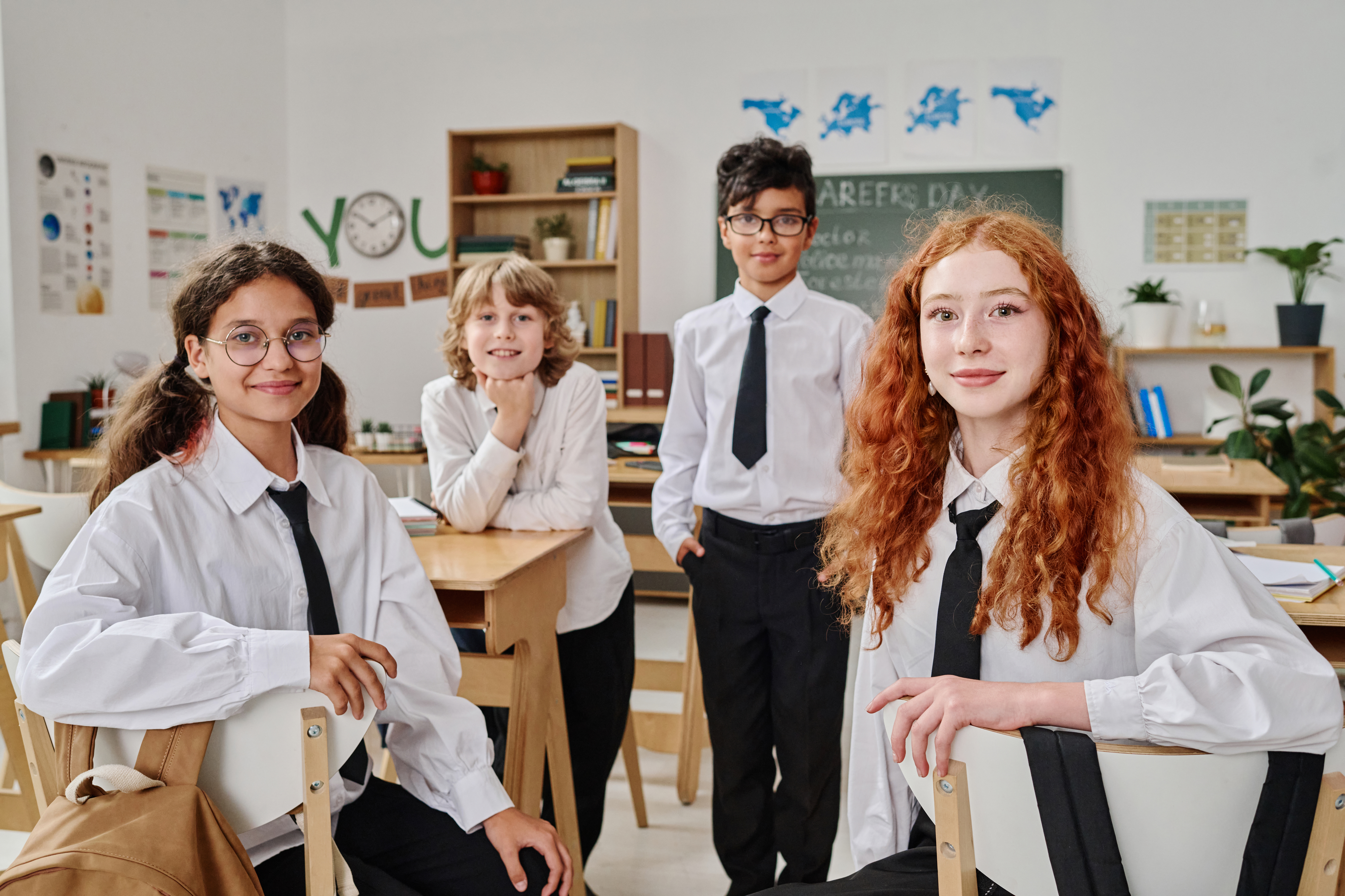 Diverse group of students in school uniforms smiling in a cozy classroom, representing the close-knit community of small independent or local schools with Pamoja.