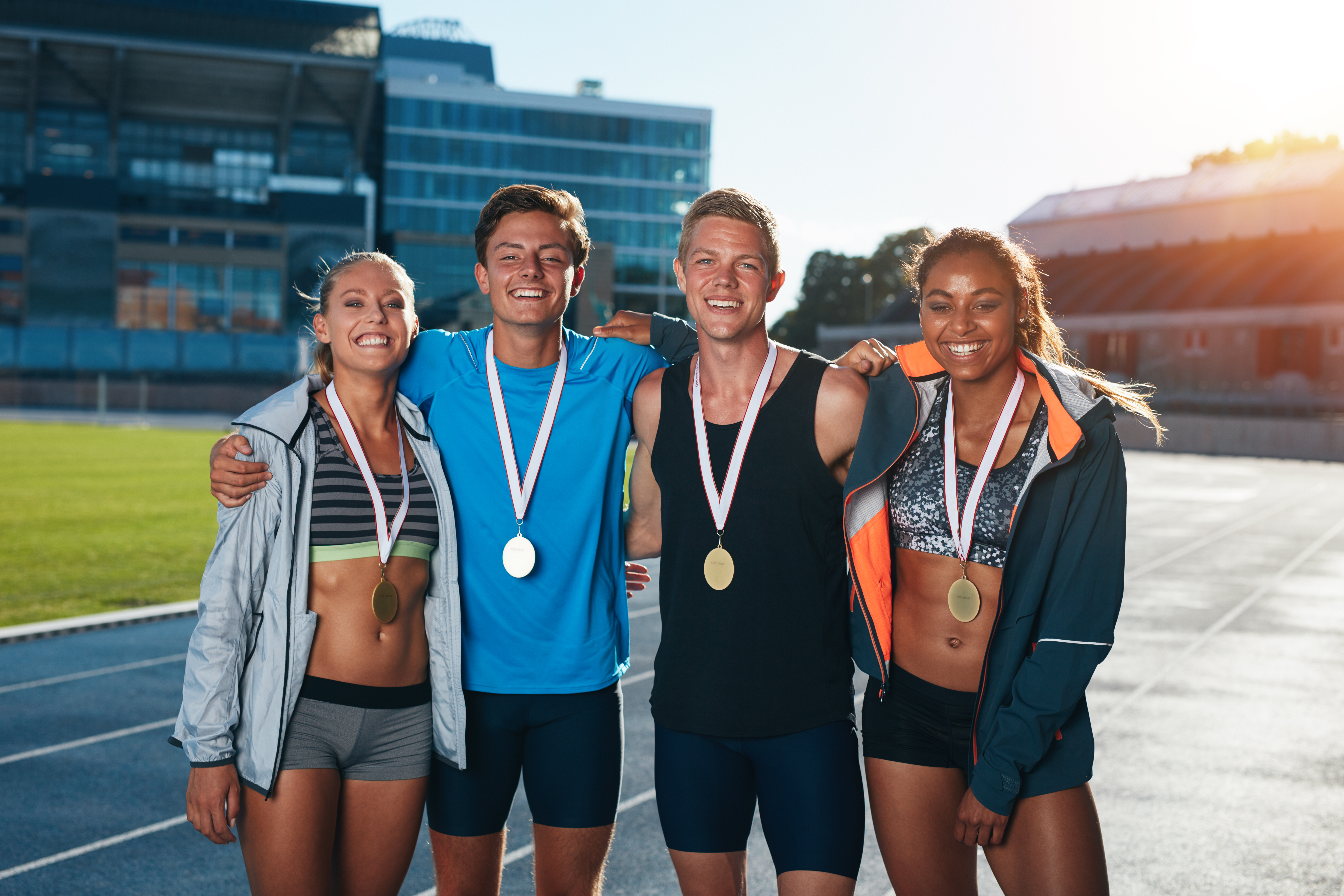 Elite student athletes wearing gold medals on a track after a competition.