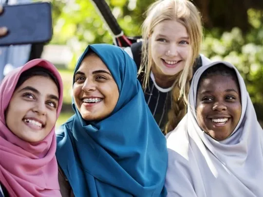 Teenagers using a phone to take a group photo.