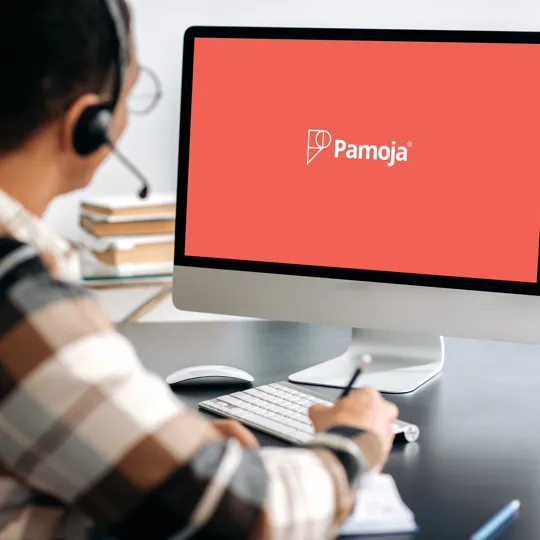 a person with a headset and a plaid shirt looking at a desktop monitor displaying the word