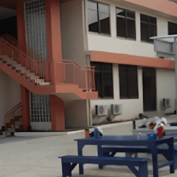 The courtyard of Lincoln Community School campus, featuring a two-story building with orange trim and outdoor seating area with blue and gray picnic tables.