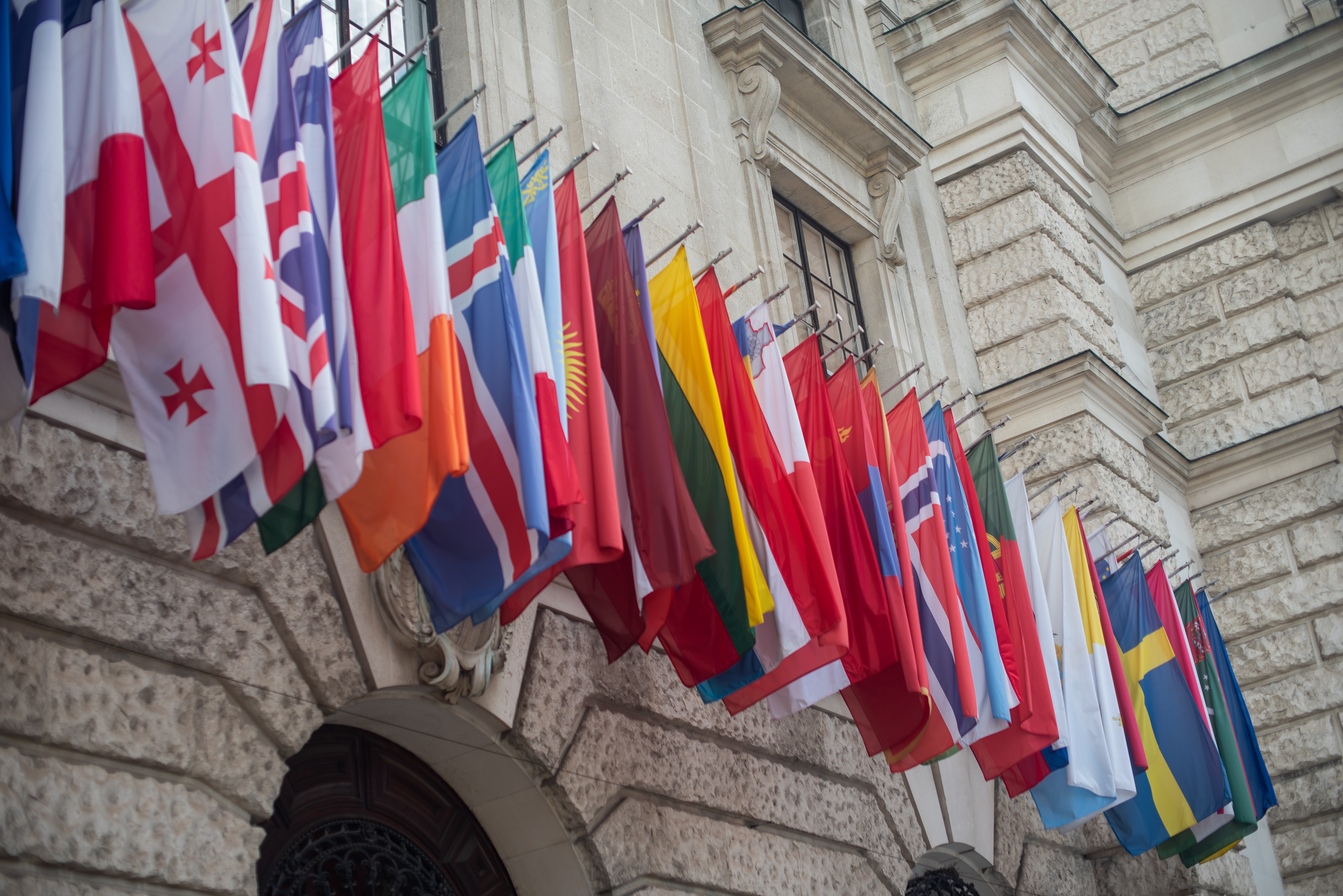International flags flying on the side of a building. 
