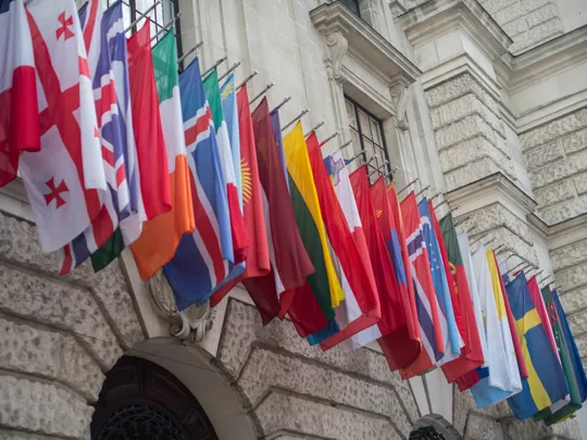 International flags flying on the side of a building.