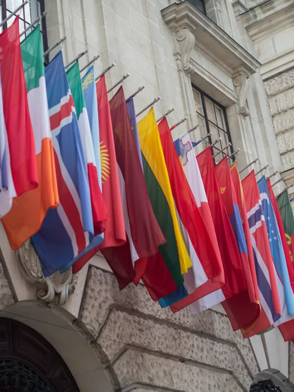 International flags flying on the side of a building.