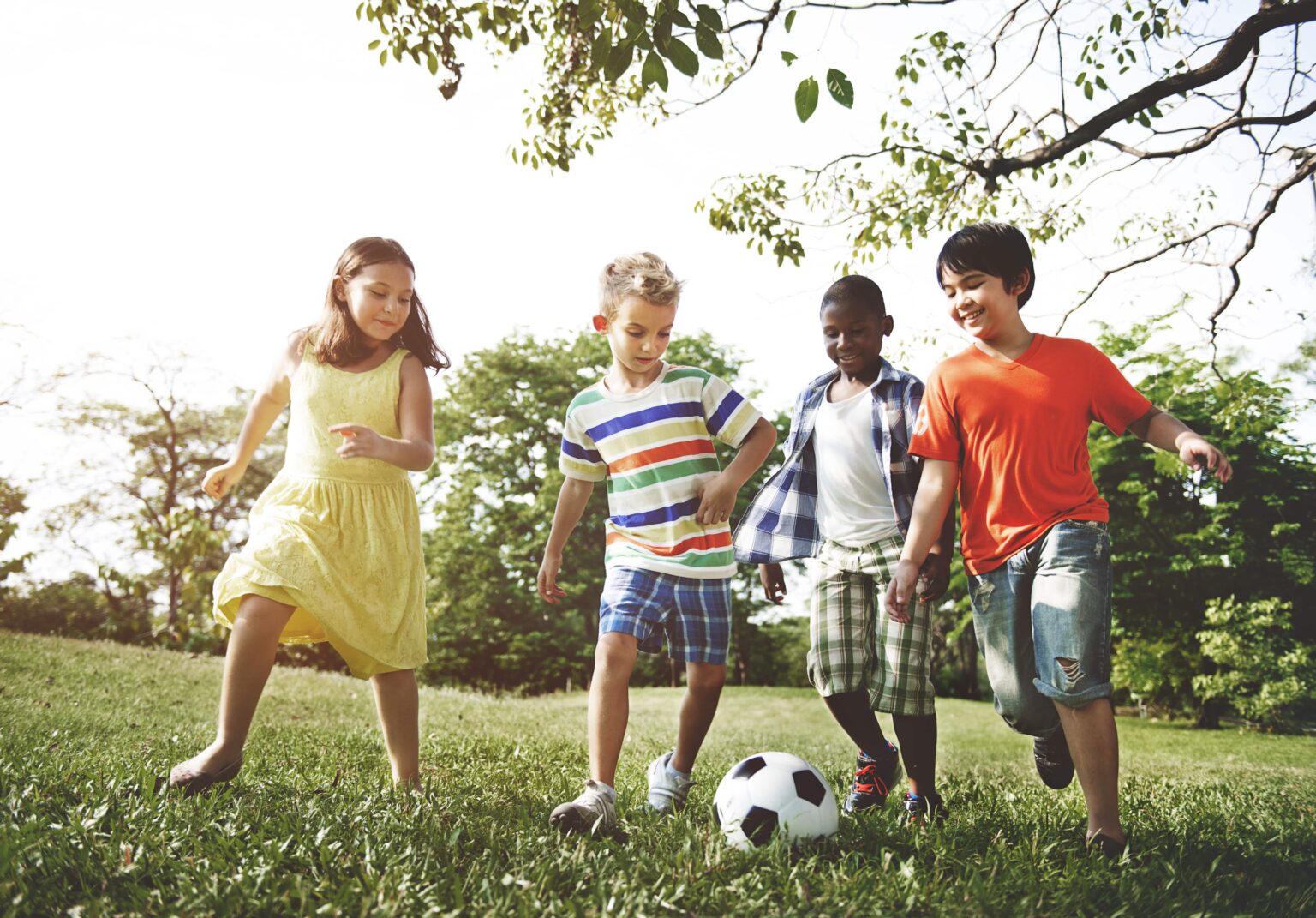 Group of young children running and kicking a football.