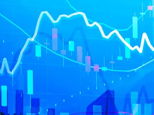 An abstract digital image with various blue-toned financial graphs and charts overlaid on a blurry background of city buildings. The image represents economic data and financial analysis.