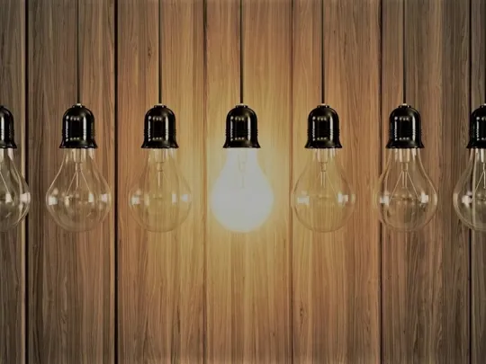 A row of lightbulbs with one of them on.