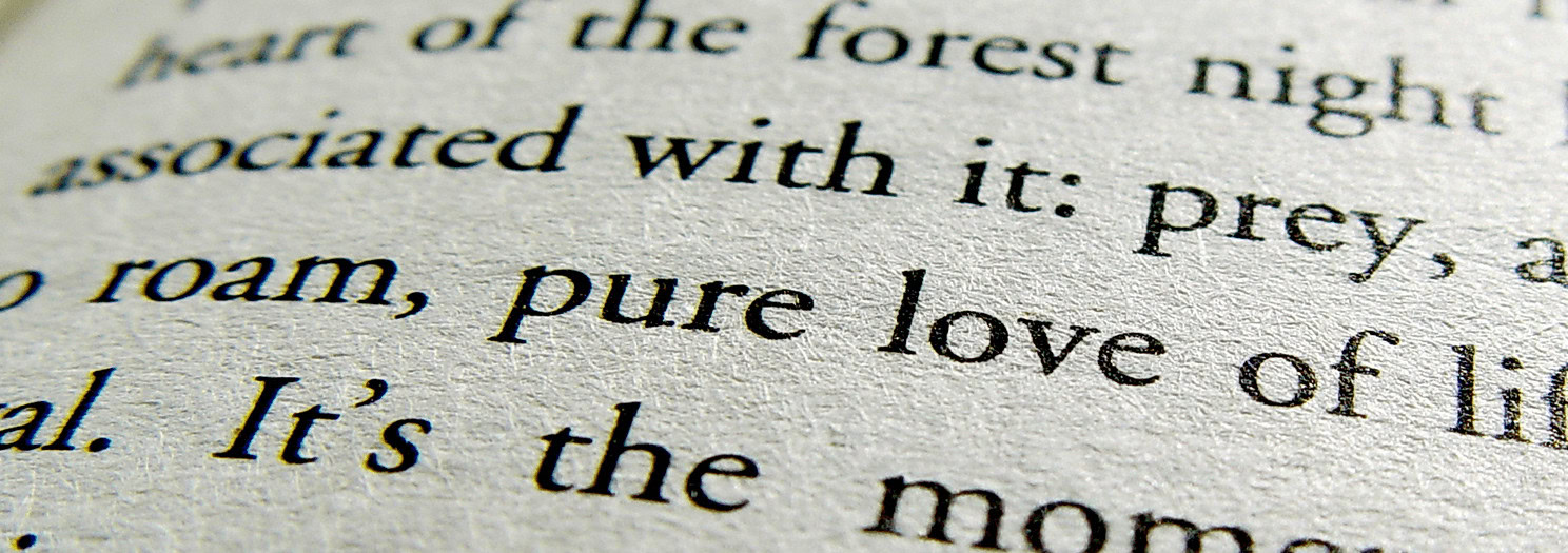A close-up, high-angle shot of an open book with black text on a light-colored page. The focus is on a few lines of text, with the words 