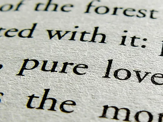 A close-up, high-angle shot of an open book with black text on a light-colored page. The focus is on a few lines of text, with the words