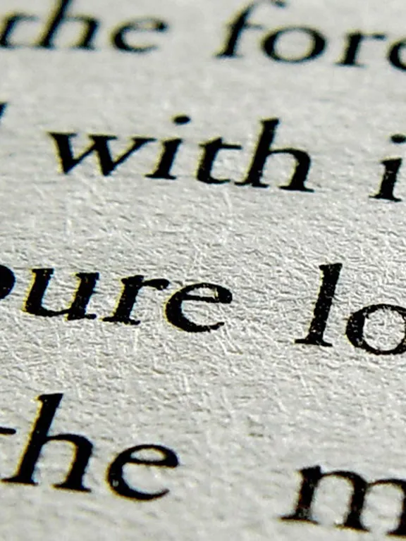 A close-up, high-angle shot of an open book with black text on a light-colored page. The focus is on a few lines of text, with the words