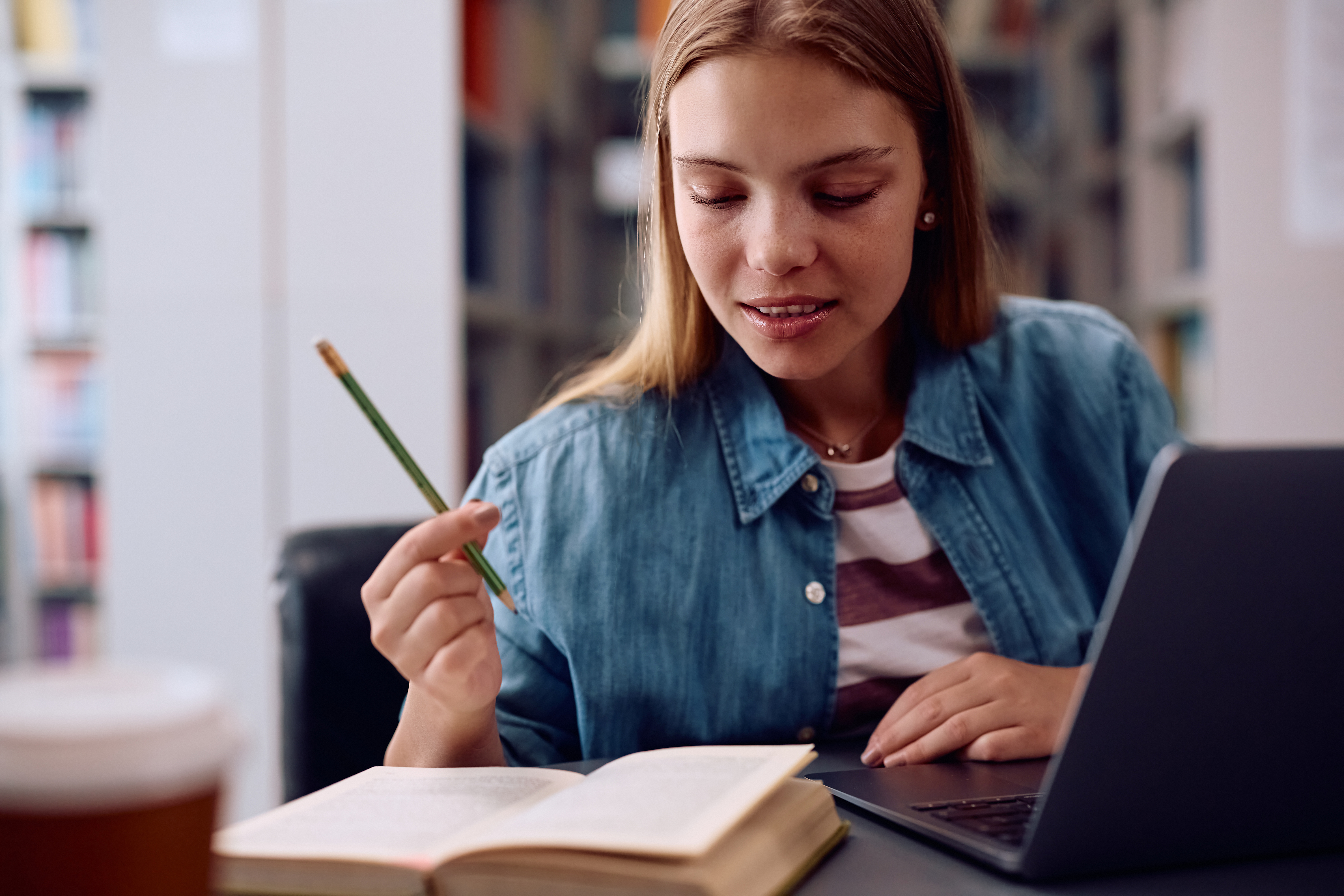 Focused young student studying with a book and laptop. This image emphasises concentration and personalised learning support for students with SEND (Special Educational Needs and Disabilities).