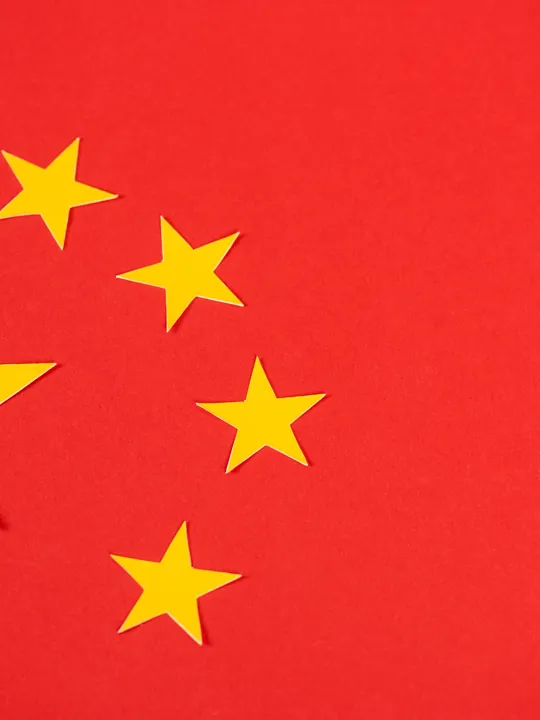 A close-up, top-down view of the red flag of the people's republic of china, featuring one large and four small yellow stars.