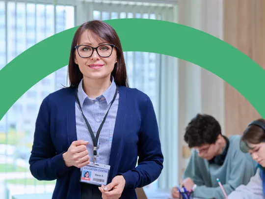 Professional teacher standing in a bright classroom with students blurred in the background