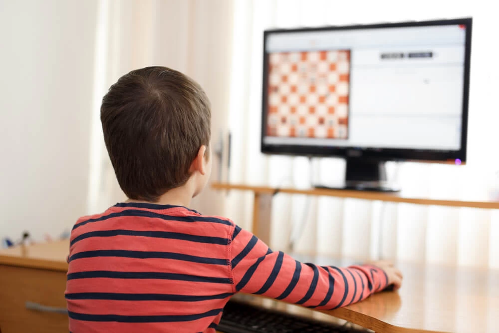 Young child playing chess on the computer.