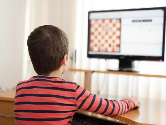 Young child playing chess on the computer.