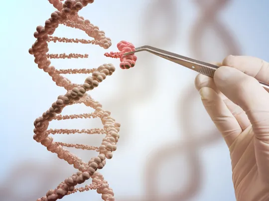 A gloved hand holds a pair of tweezers, which are being used to manipulate a small, red section of a DNA double helix. The rest of the DNA strand is a lighter, beige color and appears to be floating in a blue and white background.
