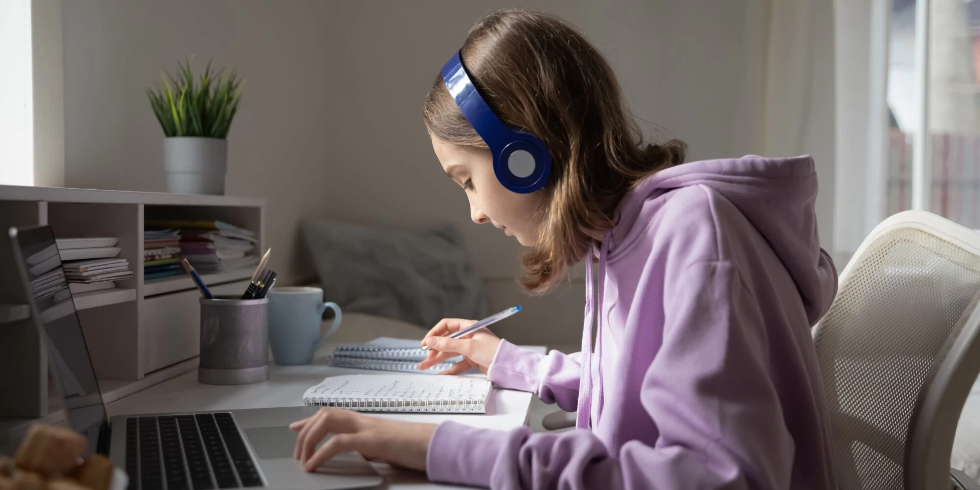 Teen student studying at desk wearing headphones. 